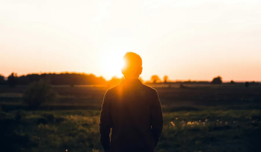 Photo of a man alone looking into the sun