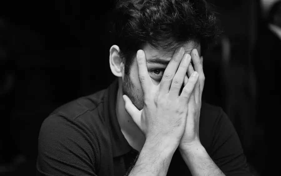 Image of a man covering his face with his hands