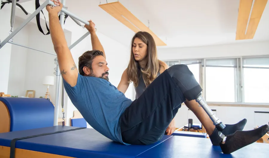 Image of a man with a prosthetic leg being assisted by physical therapist