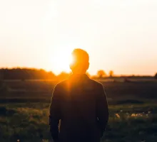 Photo of a man alone looking into the sun