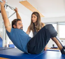 Image of a man with a prosthetic leg being assisted by physical therapist