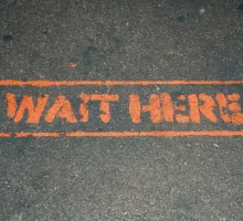 Photo of street stenciled with 'wait here'