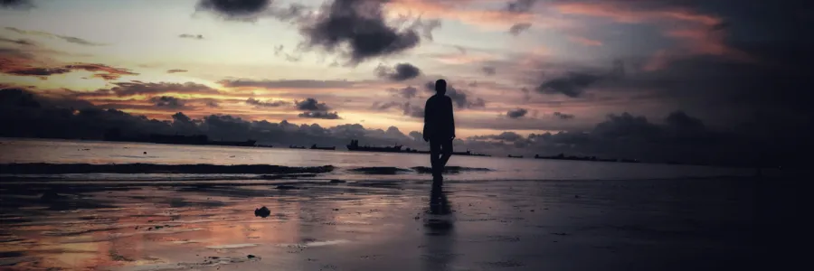 Image of solitary man on a dark beach