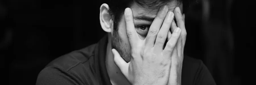 Image of a man covering his face with his hands