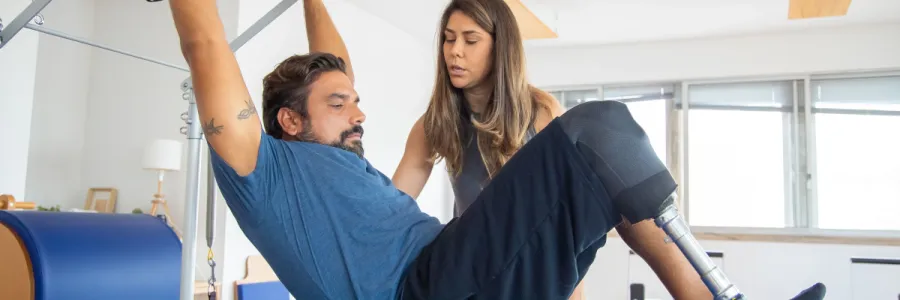 Image of a man with a prosthetic leg being assisted by physical therapist