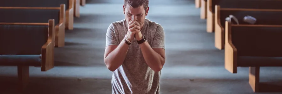 Photo of a man in prayer at the front of an empty church